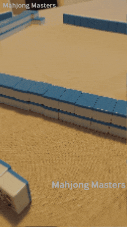 A mahjong wall of blue-backed tiles built up along the edge of the table