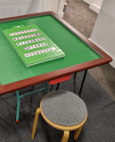 Mahjong table set up with tiles and a stool, ready to play
